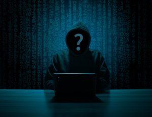 A picture of an unidentified person sitting in the dark behind a computer, representing the hacker that ruined Target’s reputation.