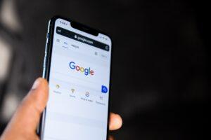 A picture of a person holding their phone with Google displayed on the screen.