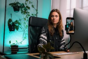 A picture of a content creator filming a video on her phone to post on her social media accounts.