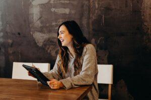 A picture of a happy customer leaving a review on her tablet for a business’s product.