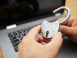 A person holding a lock hovering over their computer, representing cyber security.